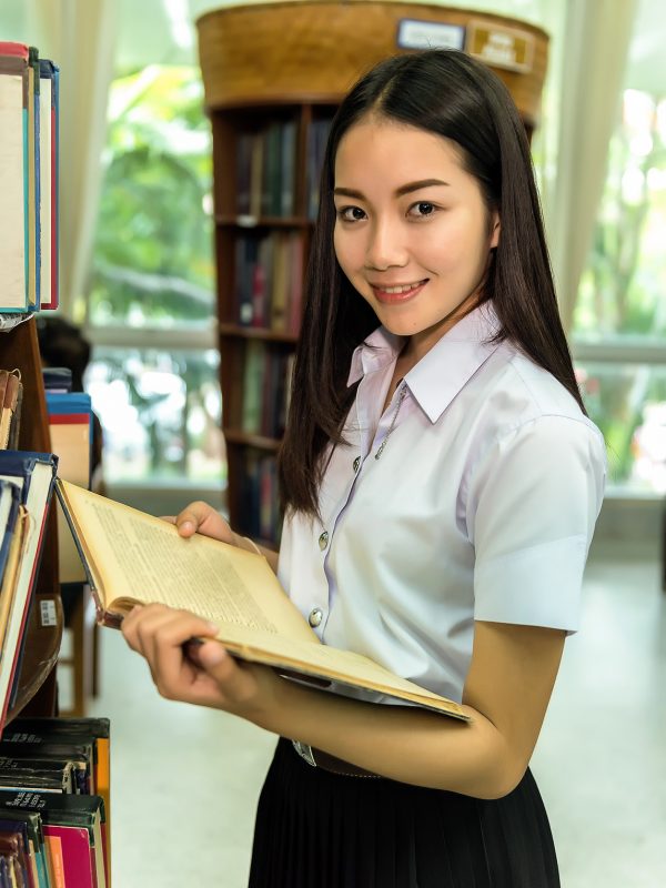 Young woman in a library, holding a book